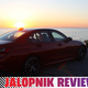 A photo of a BMW 330e Sedan with the sun setting over the ocean behind it.